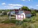 Exterior view of a white barn with red accents, sitting amid a grassy field at 12196 W Belleview Dr, Littleton, CO 80127