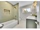 Stylish bathroom featuring green tiled shower, white hexagon tiles, and vanity with gold hardware at 7011 Poplar St, Commerce City, CO 80022