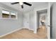Bright bedroom featuring a ceiling fan, white walls, hardwood floors, and access to additional rooms at 7011 Poplar St, Commerce City, CO 80022