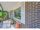Close-up of the front porch featuring seating, a window, brick detail, and wrought iron railing at 7011 Poplar St, Commerce City, CO 80022