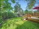 View of the backyard with a deck, mature trees, green grass and privacy fencing at 2609 S Dahlia St, Denver, CO 80222