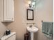 Charming powder room with a pedestal sink, decorative mirror, and a classic sconce lighting fixture at 2609 S Dahlia St, Denver, CO 80222