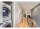 Hallway with hardwood floors, gray accent wall, and a stacked washer and dryer at 3931 Utica St, Denver, CO 80212