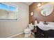 Powder room with modern dark vanity, black faucet, round mirror, designer accent wall and window at 5573 S Datura St, Littleton, CO 80120