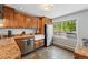 Bright kitchen features stainless appliances, farmhouse sink, tile floors, and view to the backyard at 5573 S Datura St, Littleton, CO 80120
