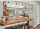 Open kitchen features an island bar with tile countertop, wooden stools, track lighting, and window view at 5573 S Datura St, Littleton, CO 80120