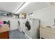 Bright laundry room featuring modern, white washer and dryer units and a utility sink for convenience at 5573 S Datura St, Littleton, CO 80120