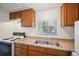 Functional kitchen with a stainless steel sink, a double basin, wooden cabinetry, and updated appliances at 5549 S Greenwood St, Littleton, CO 80120