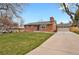 Well-maintained home featuring a brick facade, lush green lawn, and a long driveway leading to a two-car garage at 6620 S Foresthill St, Littleton, CO 80120