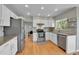 Bright kitchen featuring white cabinets, stainless appliances, granite countertops, tile backsplash, and wood floors at 5394 S Gray St, Littleton, CO 80123