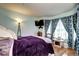 Bedroom with a lamp and TV with a bed in the center with a patterned curtain allowing natural light inside at 12183 W Cross Dr # 202, Littleton, CO 80127