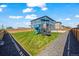 A grassy backyard includes a play structure, bordered by a wooden fence and gravel pathway, offering a fun and safe space at 902 William Way, Brighton, CO 80603