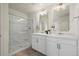Bright bathroom featuring a double sink vanity and walk-in shower with glass door at 902 William Way, Brighton, CO 80603