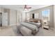 Luxurious main bedroom with a large bed, bench, ensuite bath, ceiling fan, and two bright windows at 15715 Carob Cir, Parker, CO 80134