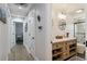 Hallway view leading to bathroom with custom vanity, shiplap walls, and glass-enclosed shower at 7440 Quail St, Arvada, CO 80005