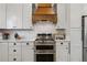 Kitchen featuring sleek appliances, white cabinetry, and stylish vent hood at 7440 Quail St, Arvada, CO 80005