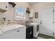 Bright laundry room with front-loading washer and dryer, storage cabinets, and a window providing natural light at 7440 Quail St, Arvada, CO 80005
