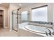 Primary bathroom with a separate shower and tub with modern fixtures and a frosted glass window at 9771 Rosalee Peak St, Littleton, CO 80125
