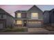 Charming two-story home with gray siding, brick accents, and a two-car garage at dusk at 9771 Rosalee Peak St, Littleton, CO 80125