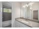 Bright bathroom featuring a grey vanity with solid surface counters, modern light fixtures, and tiled bath/shower at 1403 Valentia St, Denver, CO 80220