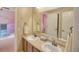 Bathroom with double vanity, a large mirror, and view to a pink themed bedroom at 735 Woodmoor Acres Dr, Monument, CO 80132