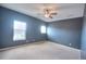 Empty bedroom with neutral carpet, light and fan and windows with a view of the yard at 735 Woodmoor Acres Dr, Monument, CO 80132