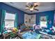 A blue-walled bedroom is cheerful with windows, a ceiling fan, and built-in corner shelving at 735 Woodmoor Acres Dr, Monument, CO 80132