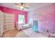 Playful bedroom with pink walls, a rainbow mural, and a cozy area rug at 735 Woodmoor Acres Dr, Monument, CO 80132
