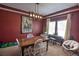 A dining room features a wood table, piano, modern light fixture, and maroon accent wall at 735 Woodmoor Acres Dr, Monument, CO 80132