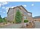 Two-story home with stone accents and a lush tree in front of an arched entryway and three car garage at 735 Woodmoor Acres Dr, Monument, CO 80132