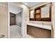 Bright bathroom featuring a modern vanity with double sinks and a dark wood cabinet with a built-in shelf and mirror at 8747 E Dry Creek Rd # 1623, Englewood, CO 80112