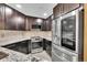 Stylish kitchen with stainless steel appliances, dark wood cabinets, and stone tile backsplash at 8747 E Dry Creek Rd # 1623, Englewood, CO 80112