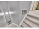 Carpeted staircase featuring a white handrail and a view into a well-lit basement with a white door at 8747 E Dry Creek Rd # 1623, Englewood, CO 80112