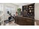 Home office with built-in shelving, desk, and exercise bike at 14681 Jinan Ave, Parker, CO 80134