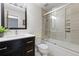 Modern bathroom with dark vanity, glass enclosed shower and tub combo with light colored wall tiles at 7507 Braun St, Arvada, CO 80005