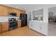 Well-equipped kitchen featuring a black fridge, modern appliances, and wood cabinets at 7507 Braun St, Arvada, CO 80005