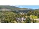 Aerial view of a home surrounded by lush green forest with a mountain backdrop on a sunny day at 1651 Pine Valley Rd, Evergreen, CO 80439