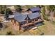 Aerial view of a log cabin home with a large deck overlooking a grassy yard, and a long driveway at 1651 Pine Valley Rd, Evergreen, CO 80439