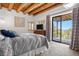 Cozy bedroom with wooden beam ceiling and access to deck with mountain views at 1651 Pine Valley Rd, Evergreen, CO 80439