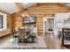 Open dining room with rustic table, view of kitchen, log walls and hardwood floors at 1651 Pine Valley Rd, Evergreen, CO 80439