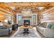 Living room featuring log walls, stone fireplace, hardwood floors, and comfortable seating at 1651 Pine Valley Rd, Evergreen, CO 80439