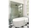 Modern bathroom features a freestanding tub, glass enclosed shower, and stylish black and white tile floor at 510 Glencoe St, Denver, CO 80220