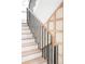 Elegant staircase featuring light wood treads, black iron railings, and decorative wall paneling at 510 Glencoe St, Denver, CO 80220