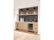 Modern wet bar area with wooden cabinets, floating shelves, and a stylish backsplash at 510 Glencoe St, Denver, CO 80220