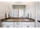Bathroom with double sinks, granite countertop, white cabinets, and decorative mirror at 11584 Pine Canyon Ln, Parker, CO 80138