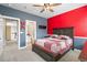 Inviting bedroom with red accent wall, neutral carpet, ceiling fan, and private bathroom at 11584 Pine Canyon Ln, Parker, CO 80138