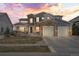 Beautiful two-story home with stone accents, a three-car garage, and professional landscaping during a colorful sunset at 11584 Pine Canyon Ln, Parker, CO 80138