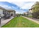 Lush backyard featuring a covered porch, patio dining set, and landscaped lawn at 8234 S Vandriver Way, Aurora, CO 80016