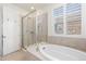 Beautiful bathroom featuring a glass-enclosed shower and a luxurious soaking tub under a large window at 8234 S Vandriver Way, Aurora, CO 80016