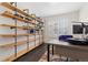 Bright home office with rustic pipe shelving, light walls, and a large desk near a window with shutters at 8234 S Vandriver Way, Aurora, CO 80016